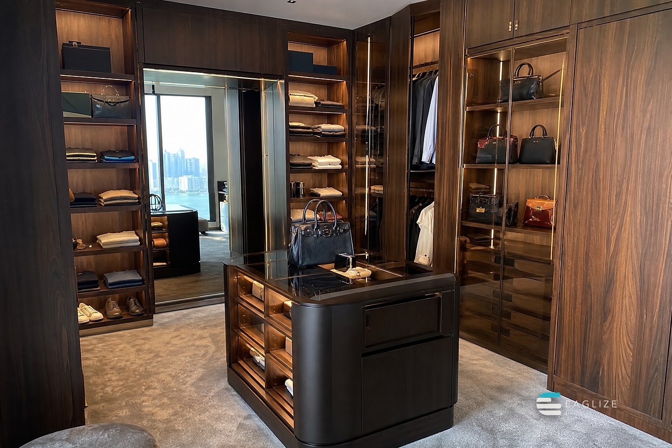 Dressing room in walnut with brass reveals, lit open shelving, glazed hanging and a fitted island