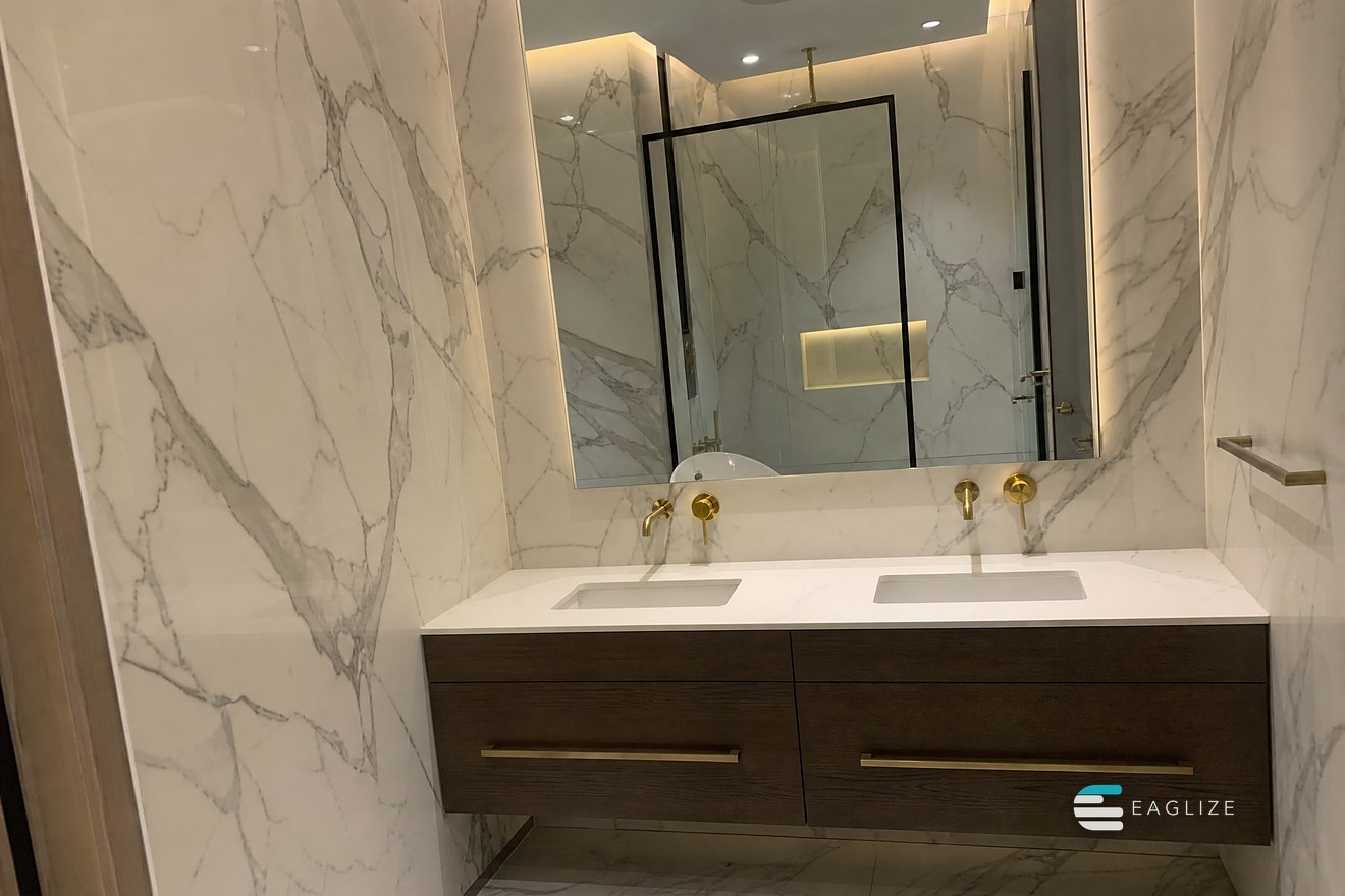 Guest bathroom with book-matched stone walls, a floating timber vanity with two basins and a backlit mirror
