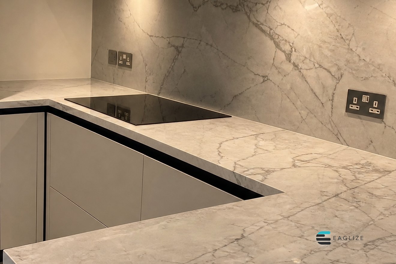 Full height stone splashback matching the worktop, with a hob set flush into handleless units