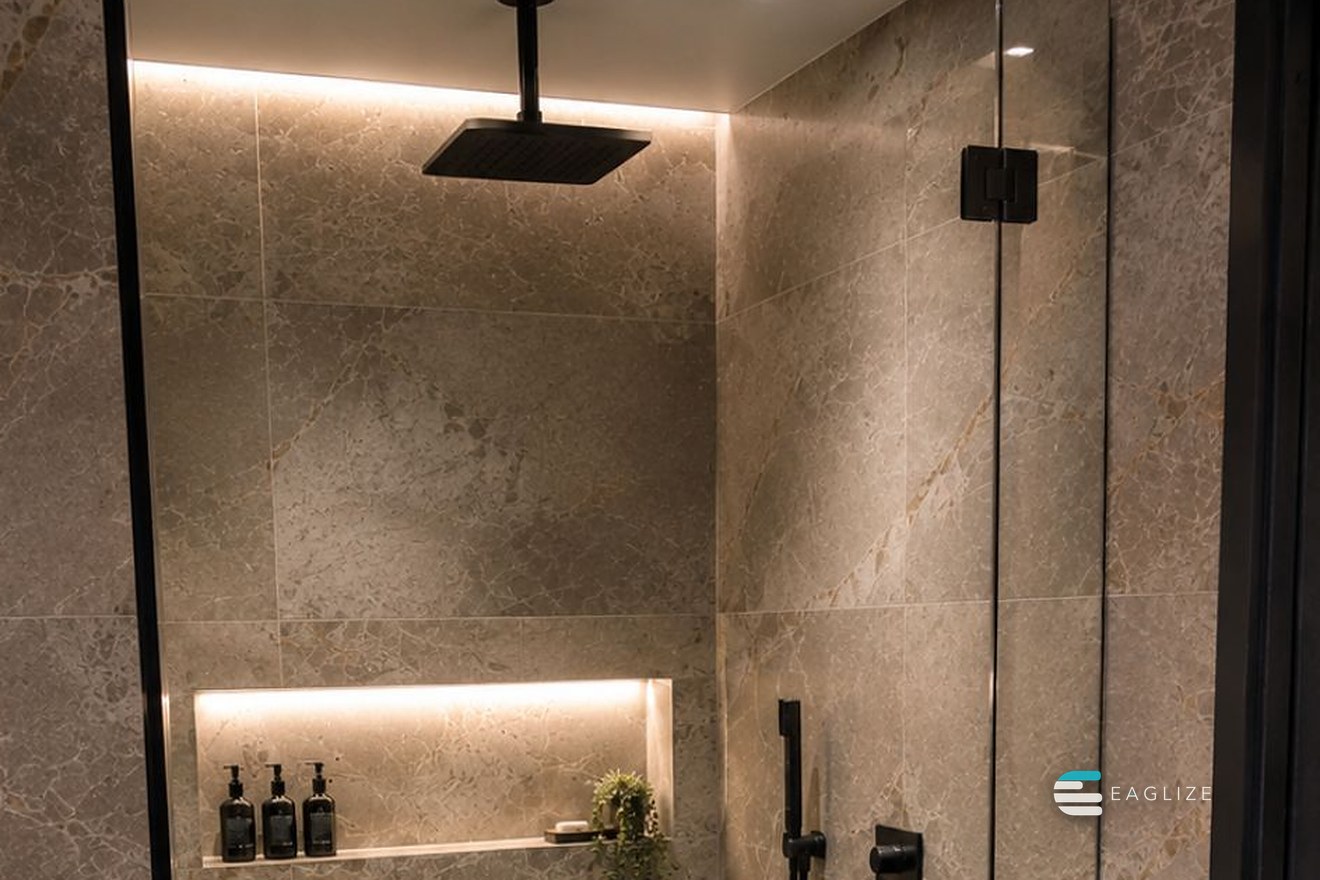 Walk-in shower in large-format marble-look slabs with a lit niche and frameless glass